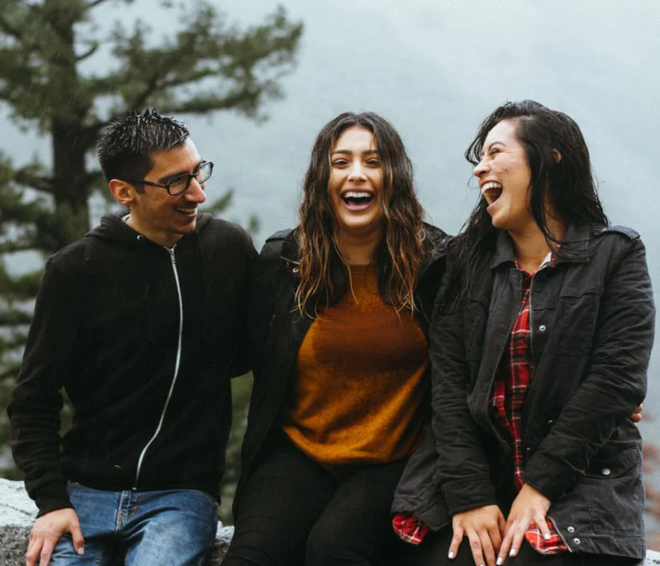 three friends laughing in the rain atop a mountain