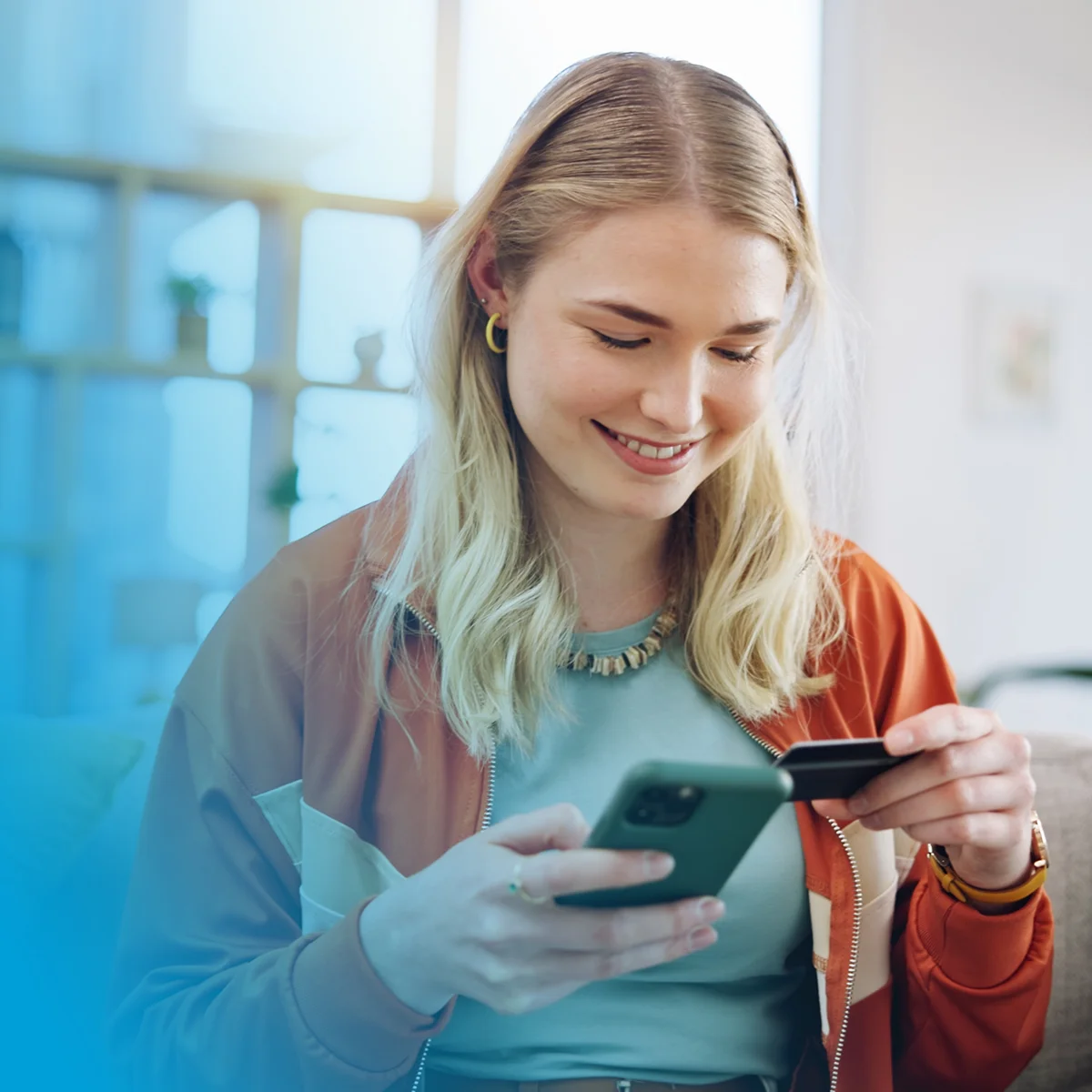 a young woman smiling, holding a phone and debit card