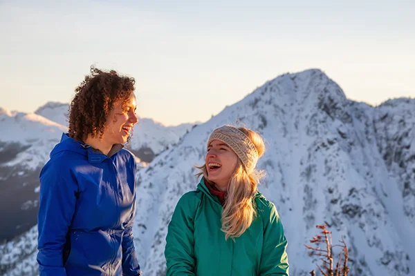 two women hiking a mountain in the winter, smiling